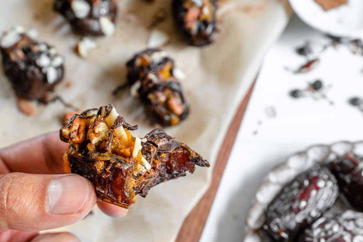 Pumpkin Spice Stuffed Dates close up with a bite taken out of it and stuffed dates in the background