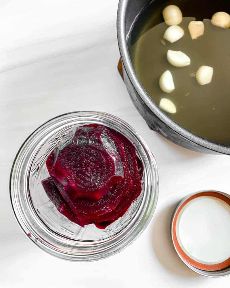 jar of Small Batch Pickled Beets with a pot of ingredients in the background