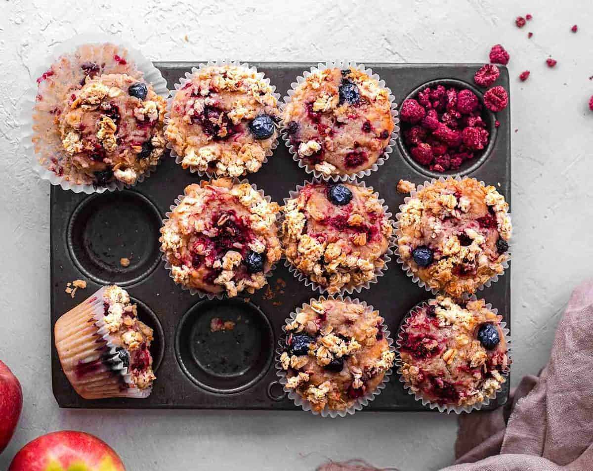 finished apple berry muffins in muffin tray against a white background