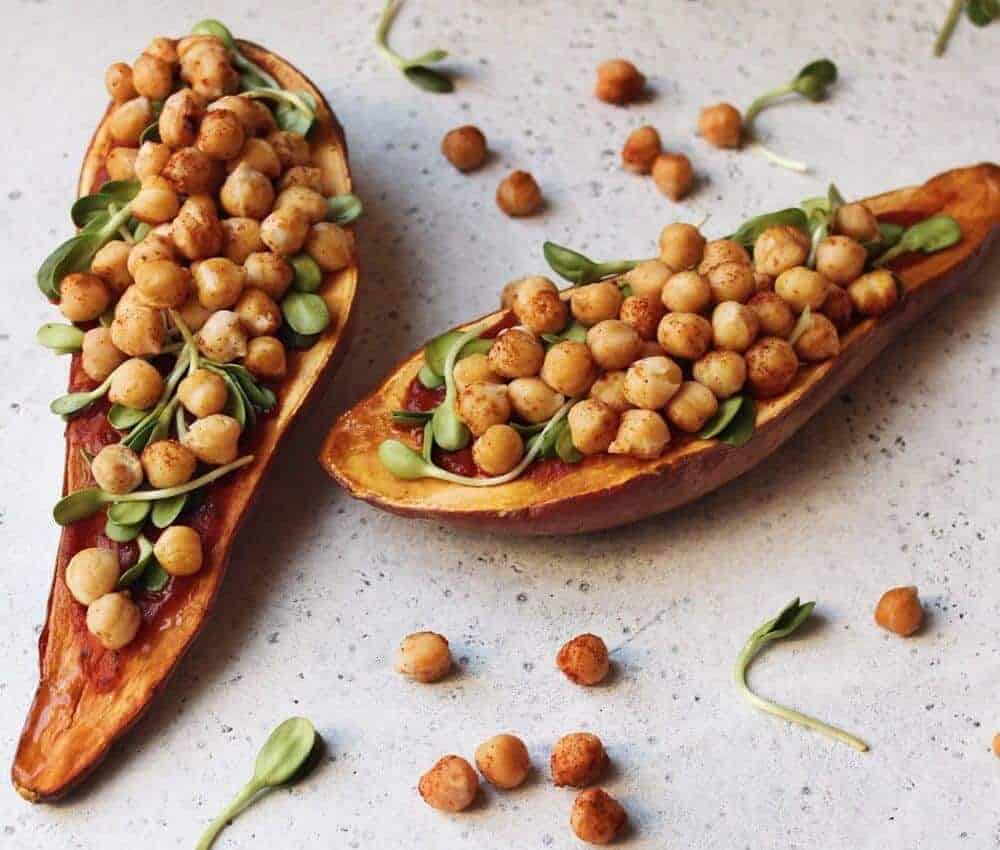 two chickpea sweet potato boats with chickpeas scattered against a white background