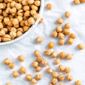 completed air fryer chickpeas scattered on a white surface and in a bowl