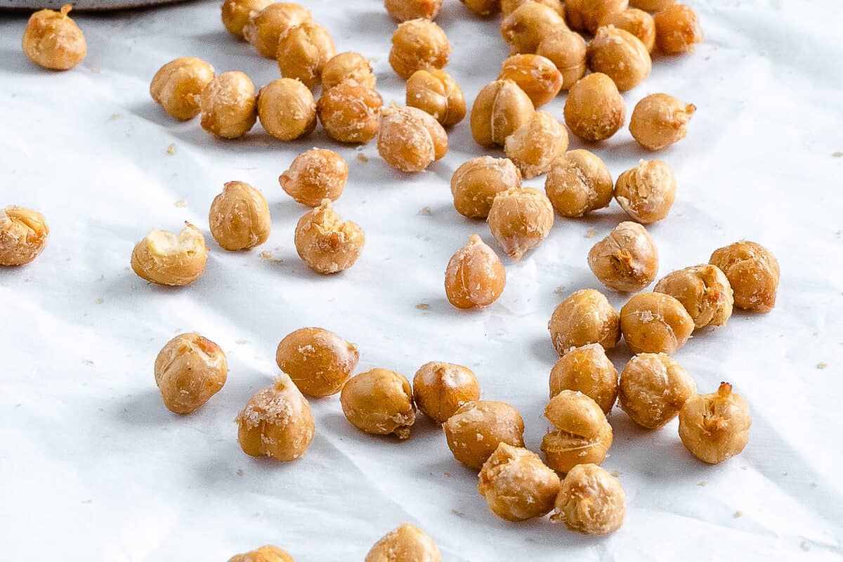 completed air fryer chickpeas scattered on a white surface and in a bowl