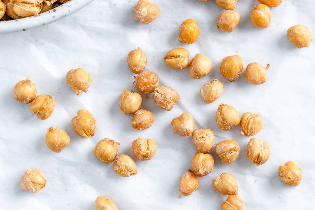 completed air fryer chickpeas scattered on a white surface and in a bowl