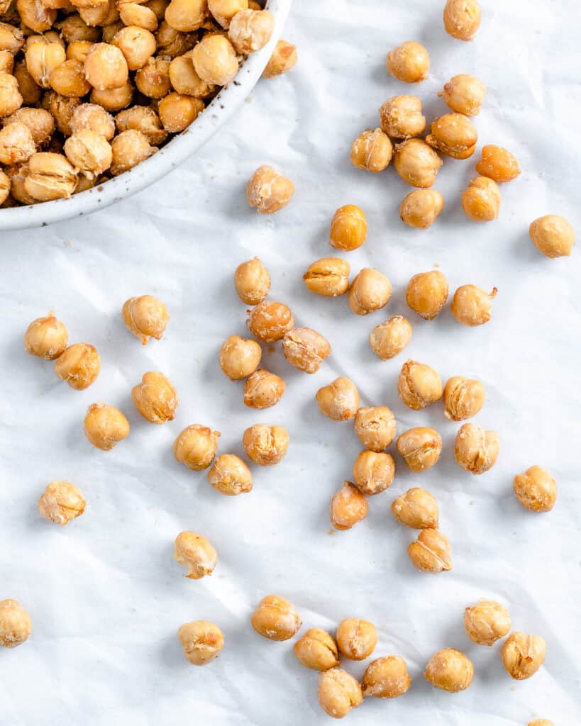 completed air fryer chickpeas scattered on a white surface and in a bowl
