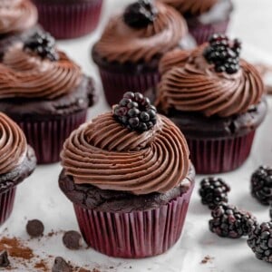 completed Blackberry Chocolate Cupcakes with blackberries scattered against a white surface