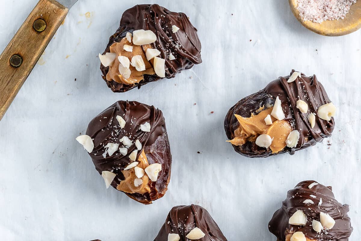 completed peanut butter stuffed dates on a white surface with ingredients in the background