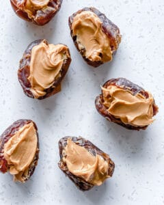 process of putting peanut butter in dates on white surface