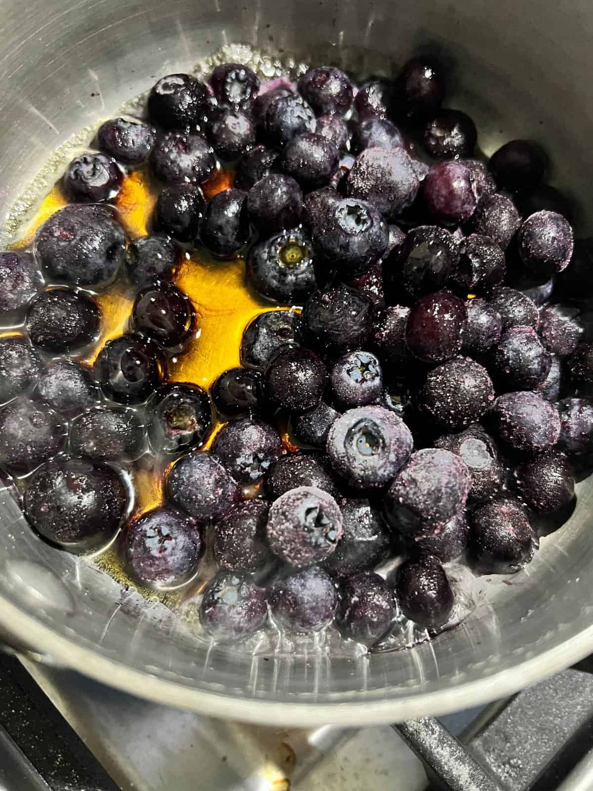 process of blueberries and maple syrup in a pot being cooked