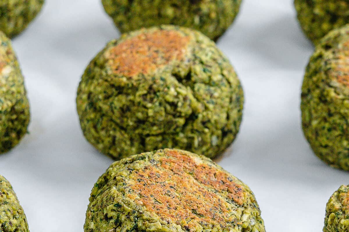 completed red lentil meatballs lined up and evenly spaced on a white surface