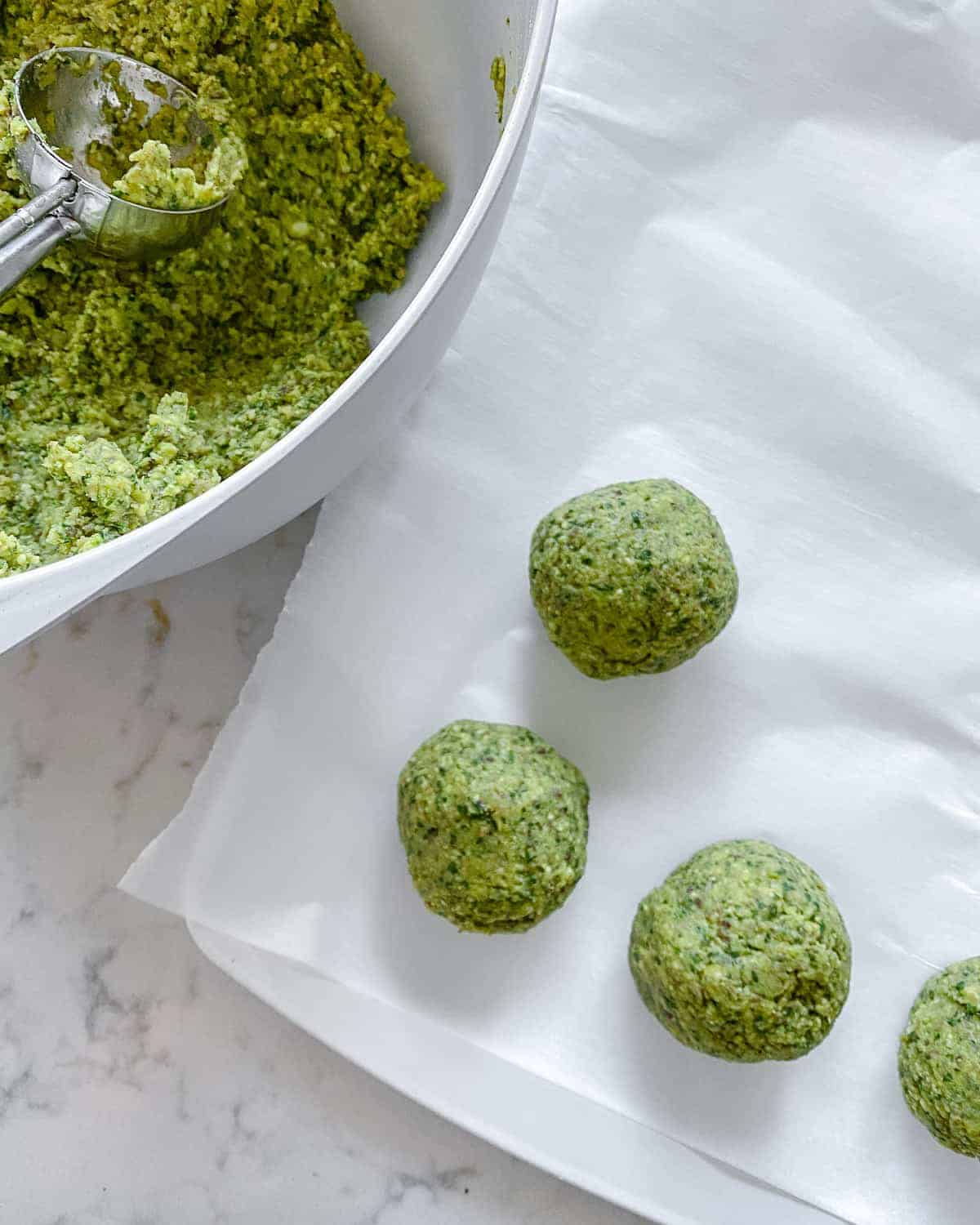 process of making formed balls of Red Lentil Meatballs mixture onto white parchment paper