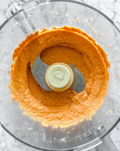 process of using a blender for the Smoky Roasted Red Pepper Hummus against a white background