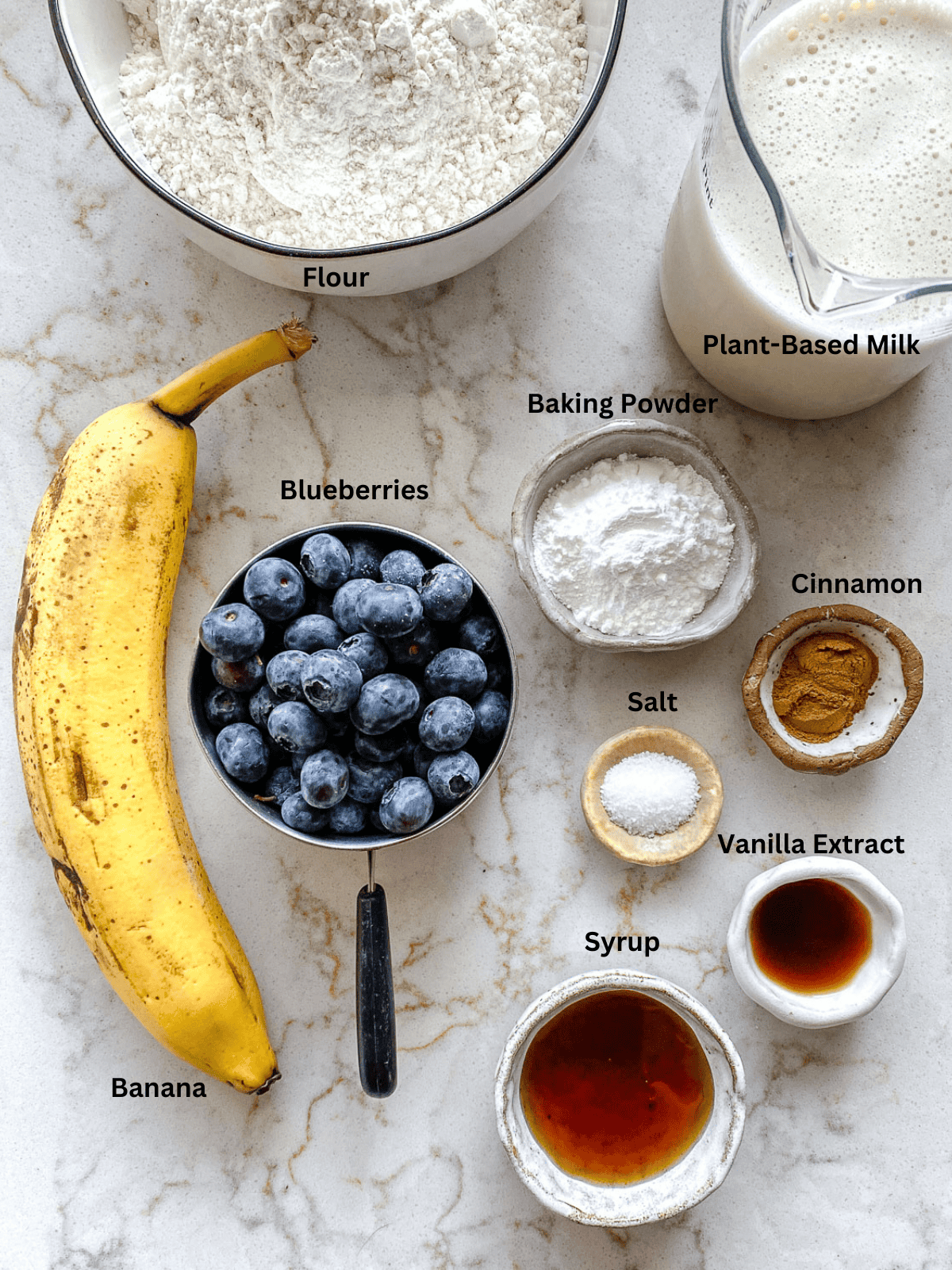 Ingredients for Blueberry Pancakes measured out on a white surface. 