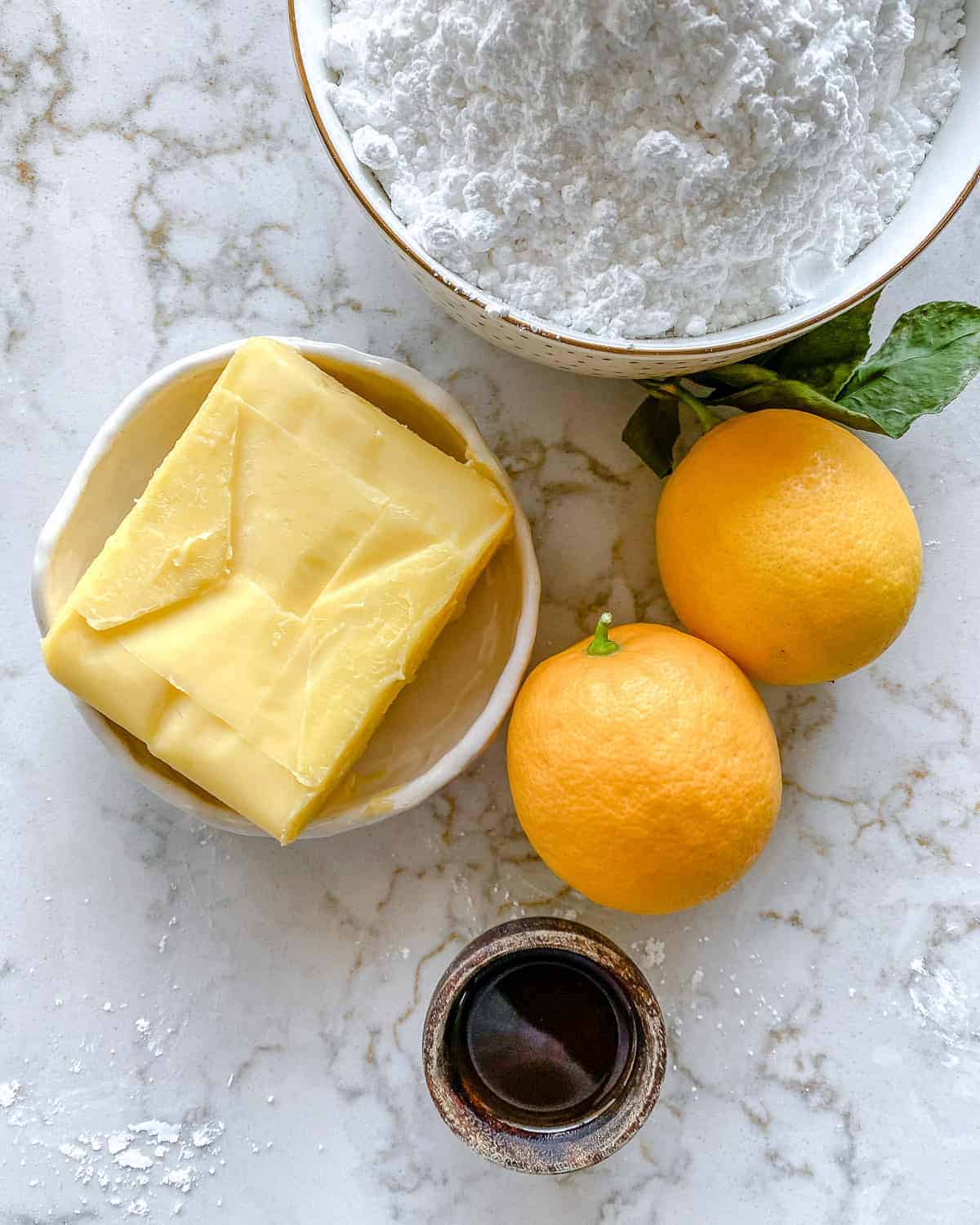 ingredients for Lemon Buttercream Frosting against white marble background