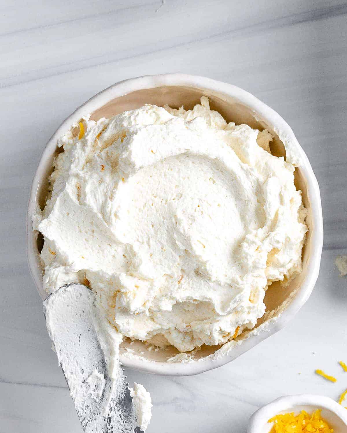 completed Lemon Buttercream Frosting in a white bowl against a white background