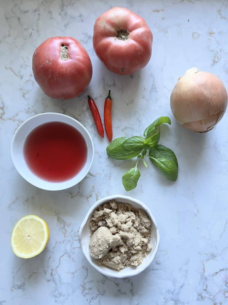 ingredients for sweet tomato chutney measured out against a white marble surface