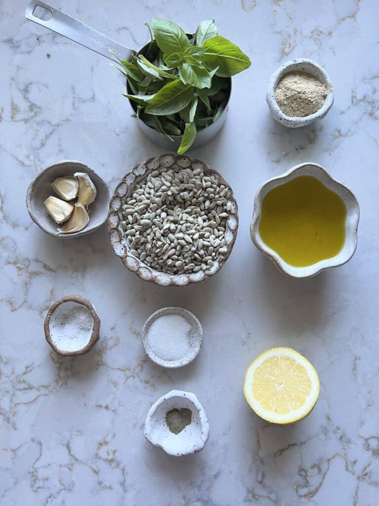 ingredients for sunflower seed pesto measured out against a white marble surfae