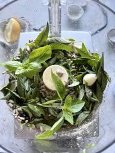 process of adding ingredient for Sunflower Seed Pesto into a blender