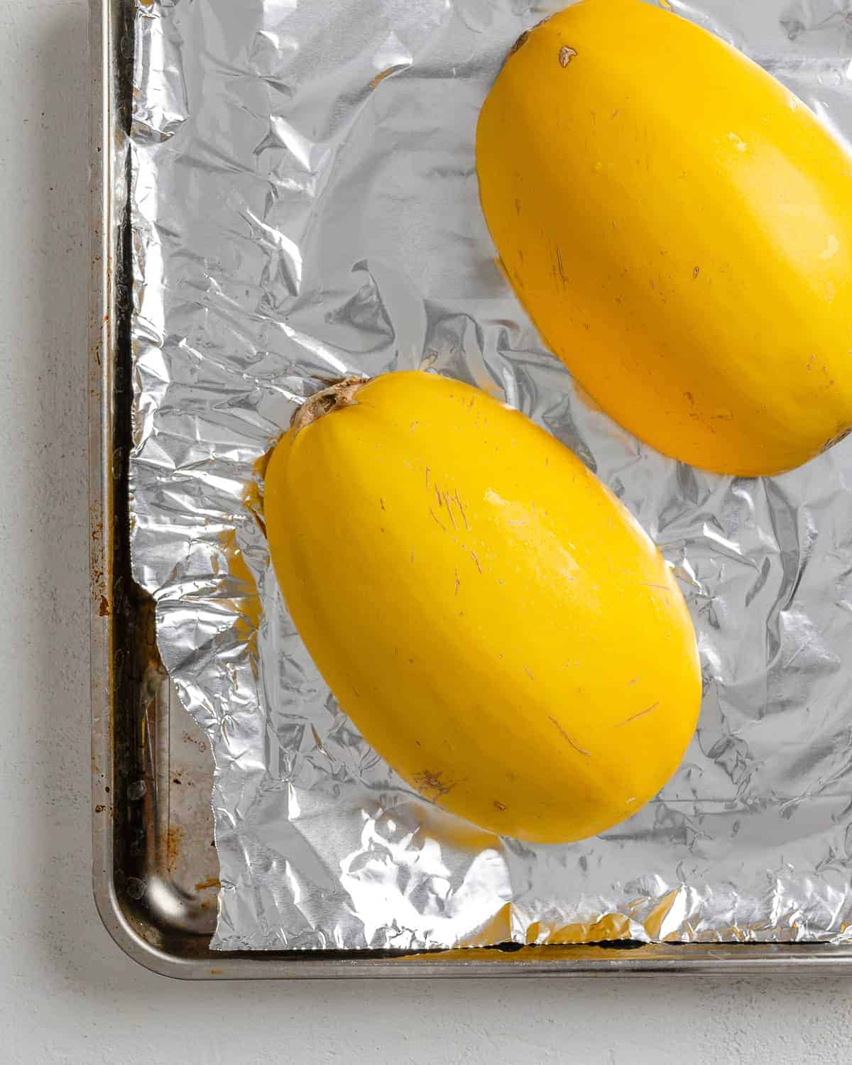 halved squash on top of foil in baking tray