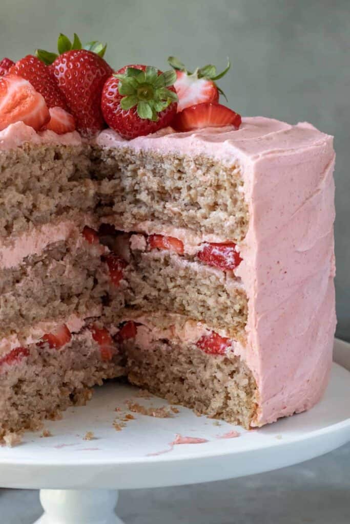 completed Vegan Strawberry Cake showing a piece missing and the layers of the cake