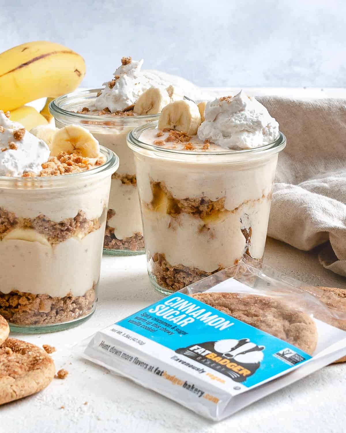 several completed banana parfait in glass jars with a cookie in the forefront