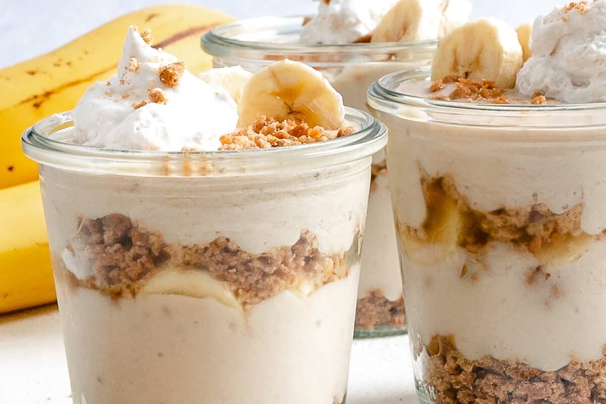 several completed banana parfait in glass jars against a white background