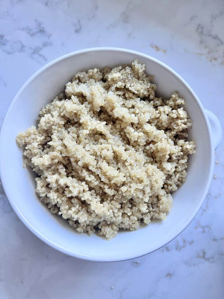 quinoa in a white bowl against a white marble surface