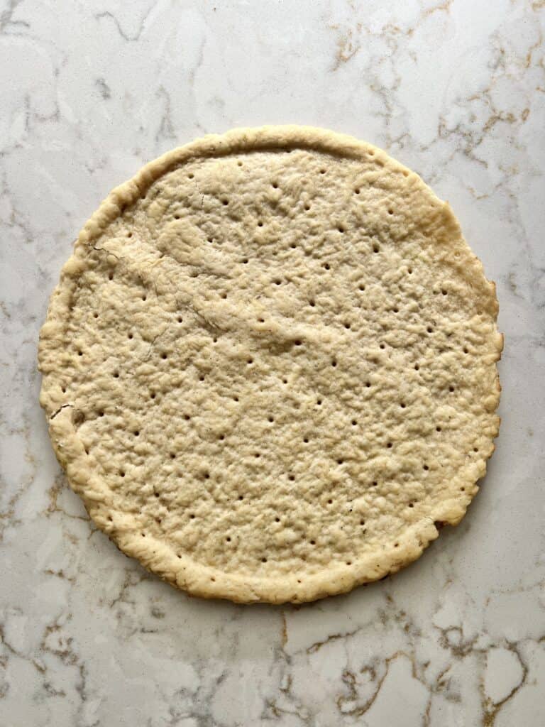 one pizza crust on a white marble surface