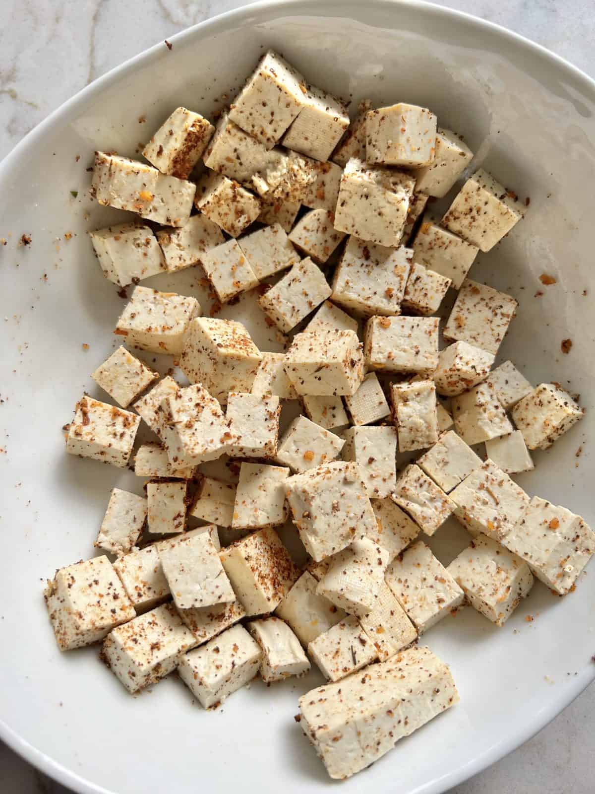 process of mixing ingredients iwth tofu in white bowl