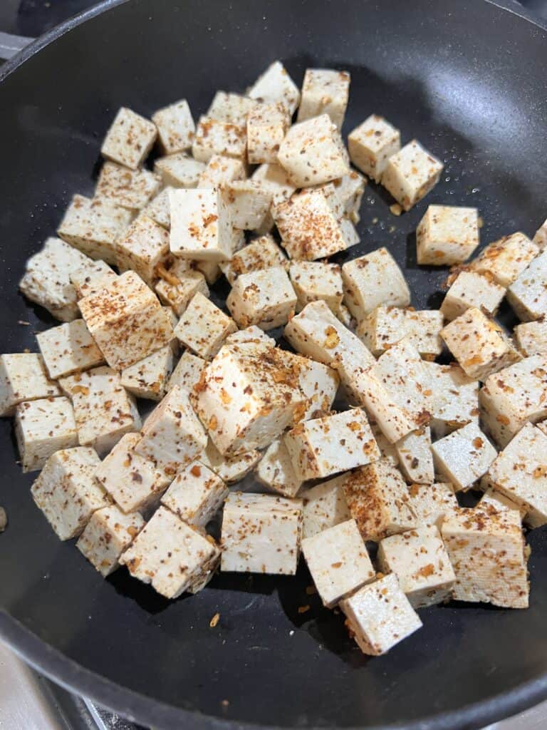 process of cooking tofu on black pan