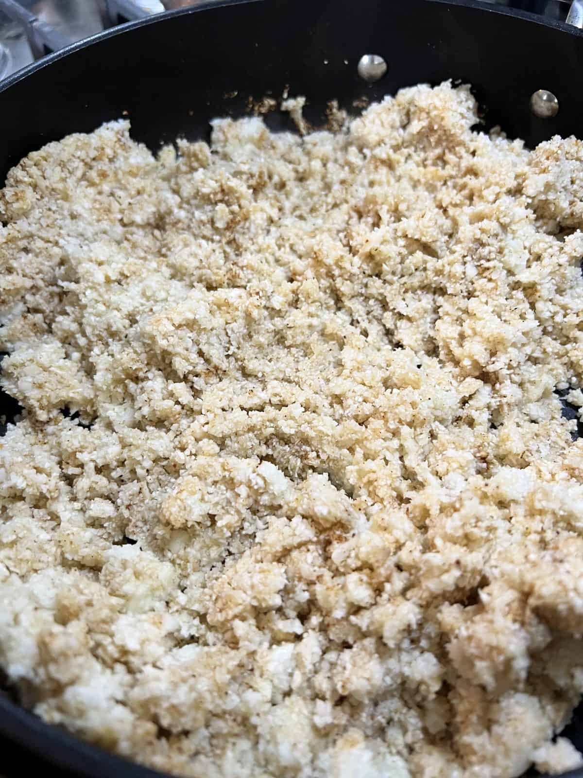post mixing cauliflower rice and seasoning in black pan