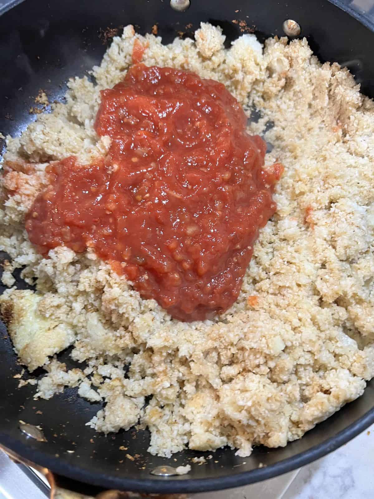 addition of salsa to cauliflower rice in black pan