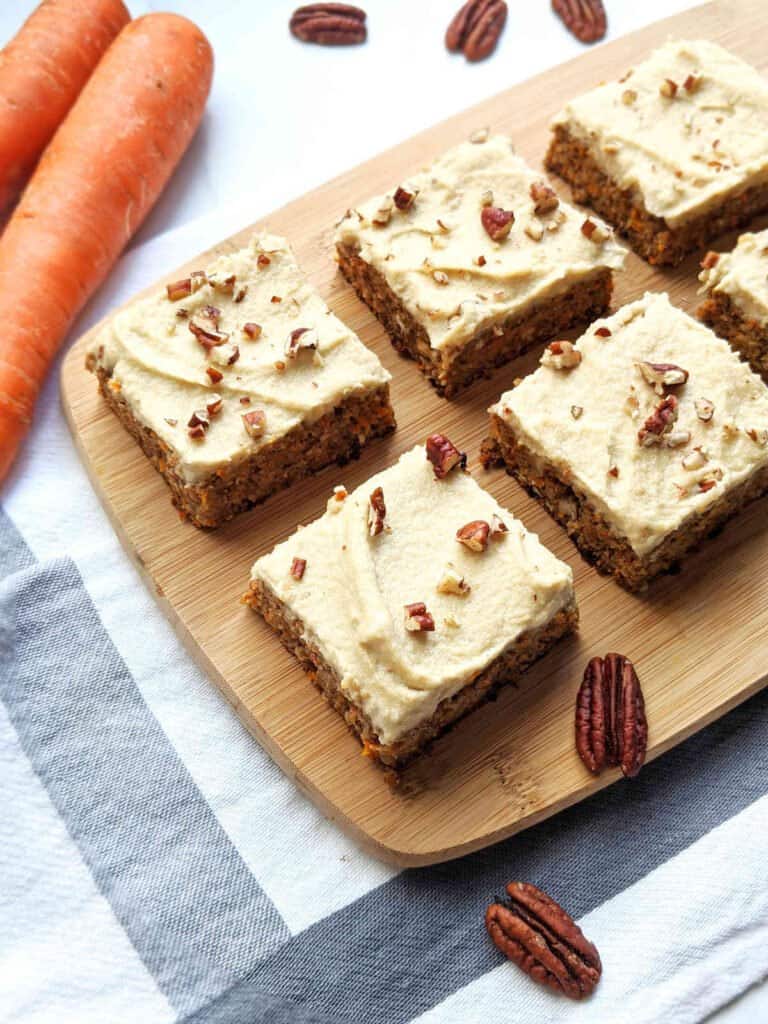 completed Vegan Carrot Cake sliced into square slices on a brown cutting board