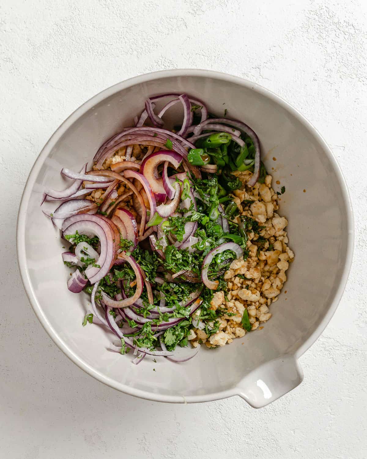 ingredients for larb salad in a white bowl against a white background