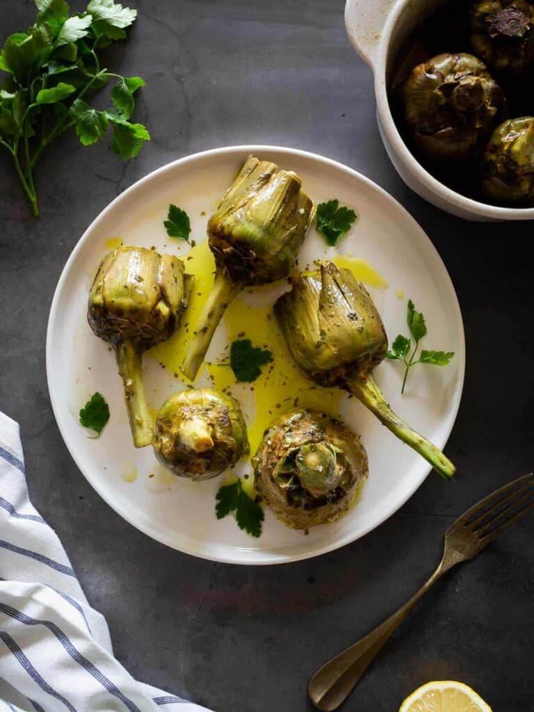 completed Roman-Style Artichokes plated on a white plate against a dark background