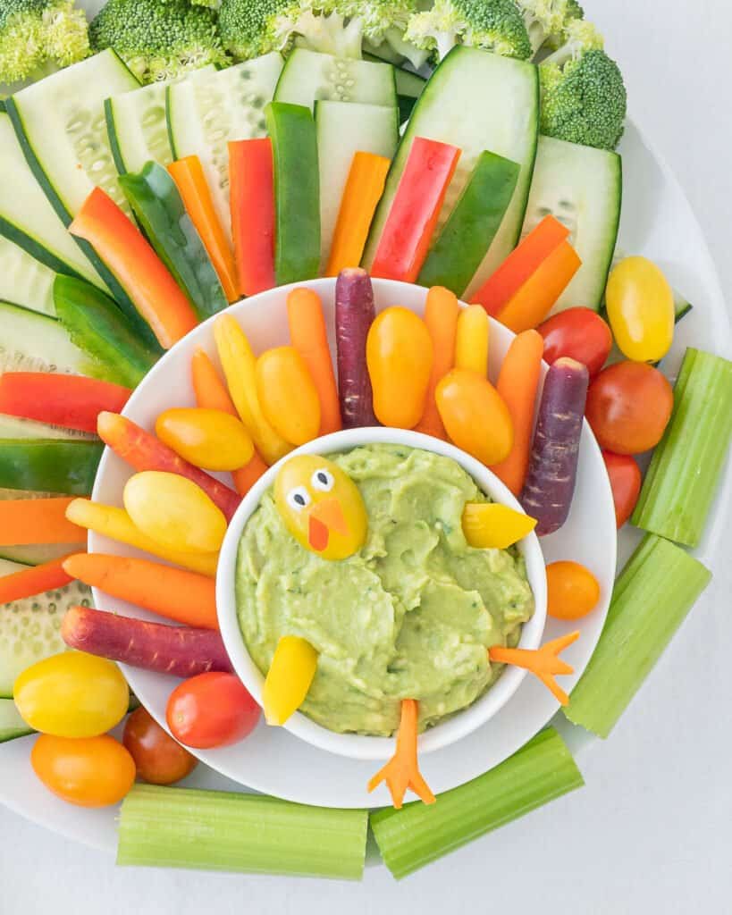 completed Veggie Tray with several veggies and guac plated on a white surface