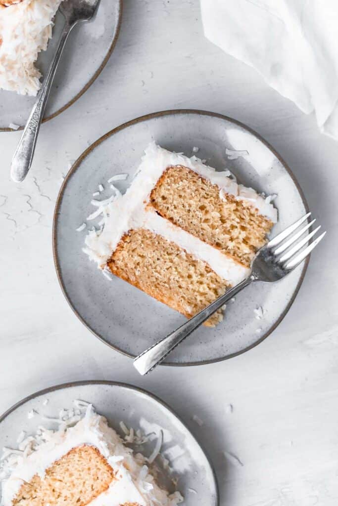 completed Vegan Coconut Cream Cake piece on a white plate against a white background