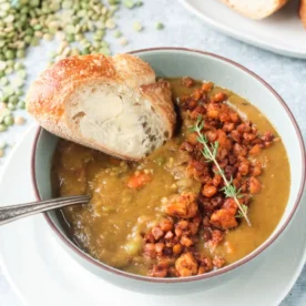 completed vegan split pea soup in a white bowl with bread in the background against a white surface