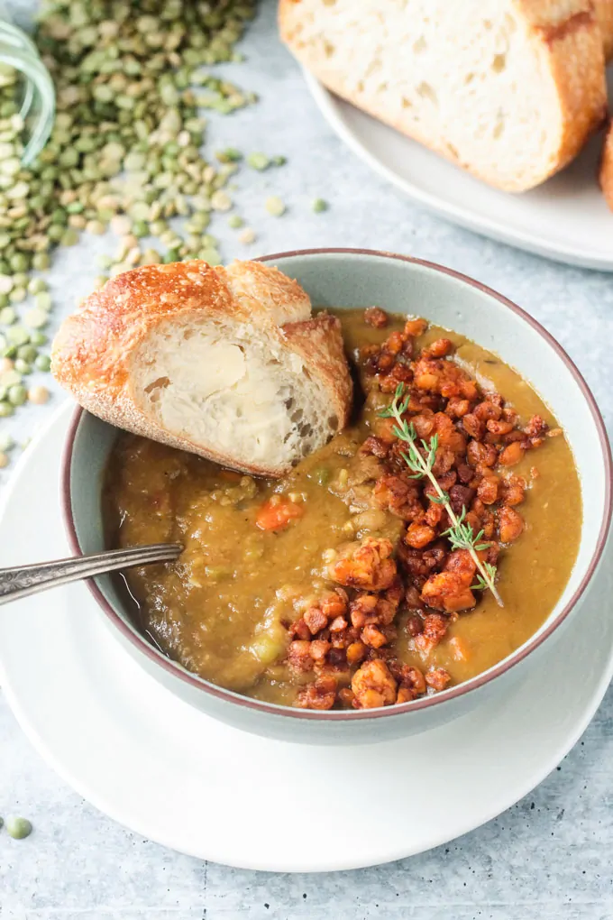 completed vegan split pea soup in a white bowl with bread in the background against a white surface