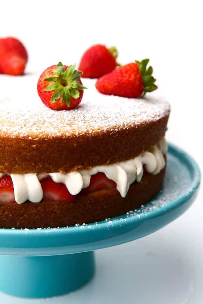 completed vegan sponge cake on a blue cake tray against a white background