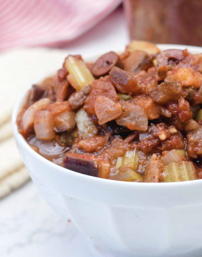 completed vegan caponata in a white bowl against a white background