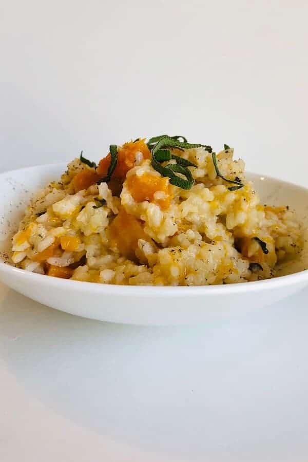 completed vegan risotto in a white bowl against a white background