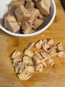 shredded jackfruit on a cutting board alongside a bowl of jackfruit in a bowl