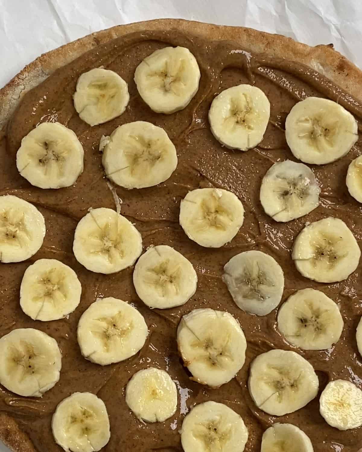 process of adding sliced bananas to fruit pizza
