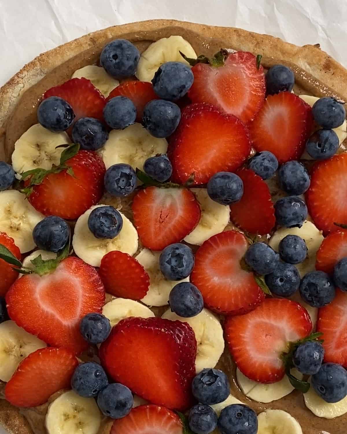 process of adding blueberries to fruit pizza