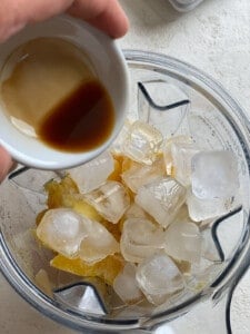 process shot of adding vanilla extract to blender