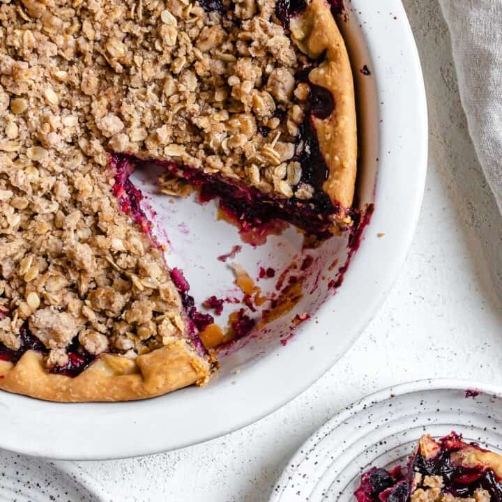 completed Mixed Berry Crumb Pie with a piece plated on a small white plate