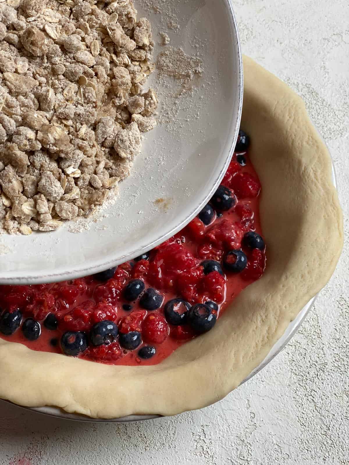 process of adding crumb topping on top of berry mixture