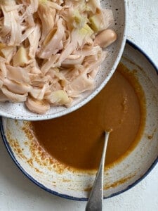 process shot of adding jackfruit into bowl of sauce
