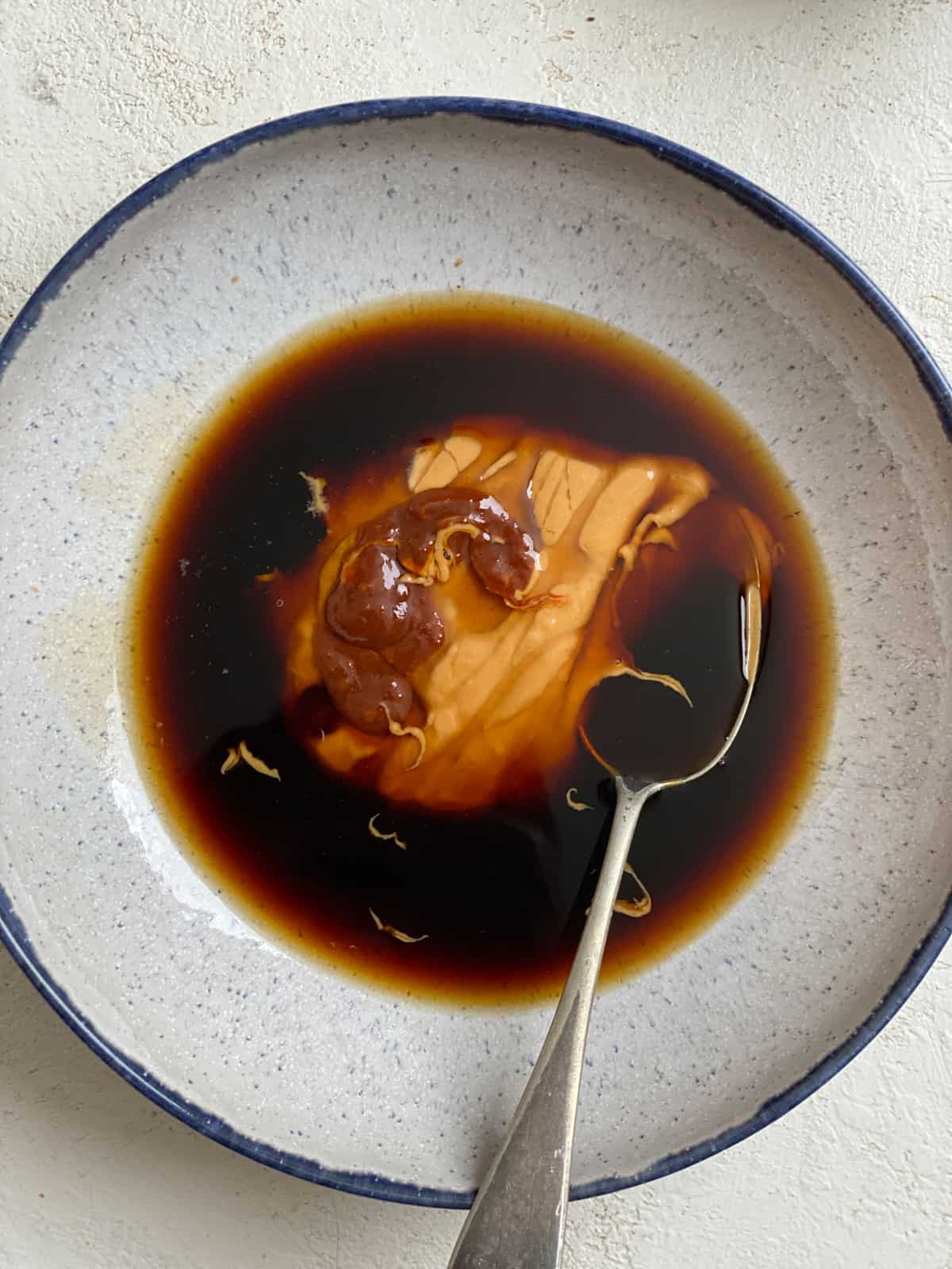 process of mixing peanut butter and soy sauce in a bowl