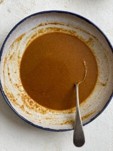 process of mixing peanut butter and soy sauce in a bowl